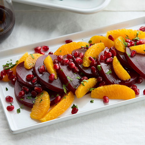 A plate of beetroot salad with sliced oranges and pomegranate seeds.